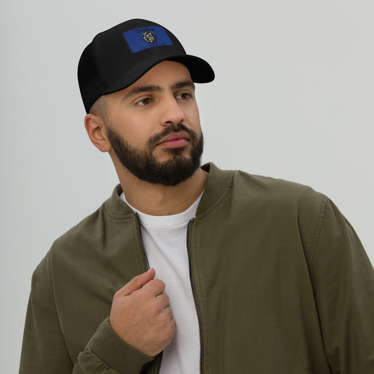 Man wearing a black cap with a blue logo and a green jacket on a plain background